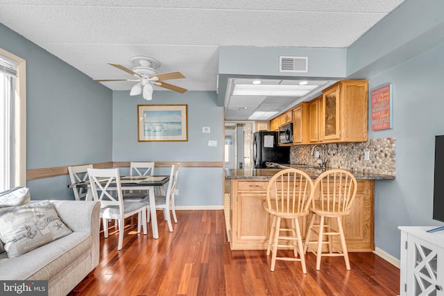 kitchen with tasteful backsplash, visible vents, dark wood finished floors, a ceiling fan, and black appliances