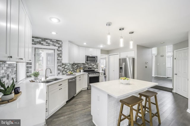 kitchen featuring appliances with stainless steel finishes, dark wood finished floors, a sink, and backsplash