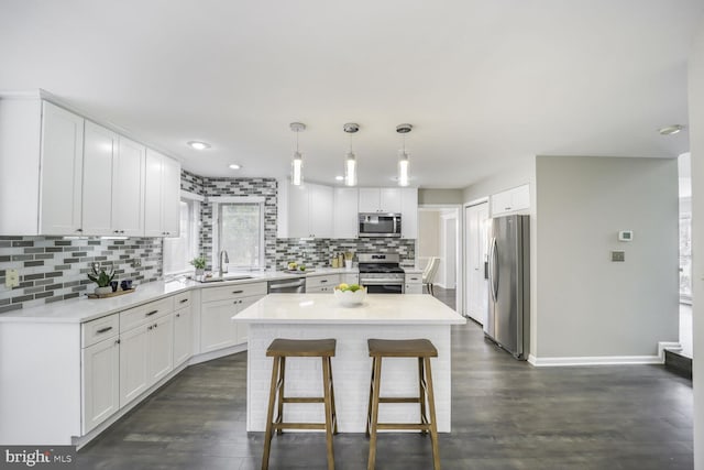 kitchen featuring white cabinets, dark wood-style floors, a breakfast bar, stainless steel appliances, and a sink