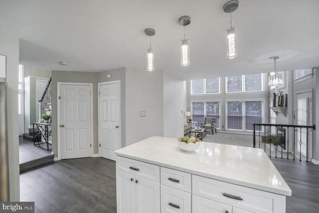 kitchen with dark wood-type flooring, light countertops, white cabinets, and decorative light fixtures