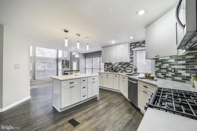 kitchen featuring appliances with stainless steel finishes, a center island, light countertops, and a sink