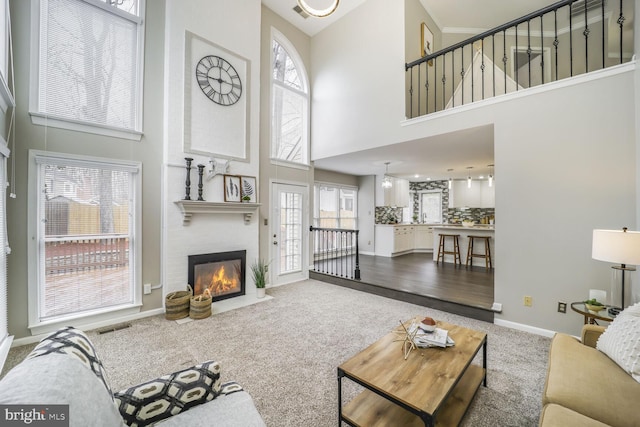 living room featuring carpet, a fireplace, visible vents, and a wealth of natural light