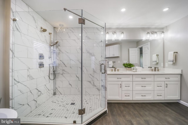 full bathroom with a stall shower, wood finished floors, a sink, and double vanity