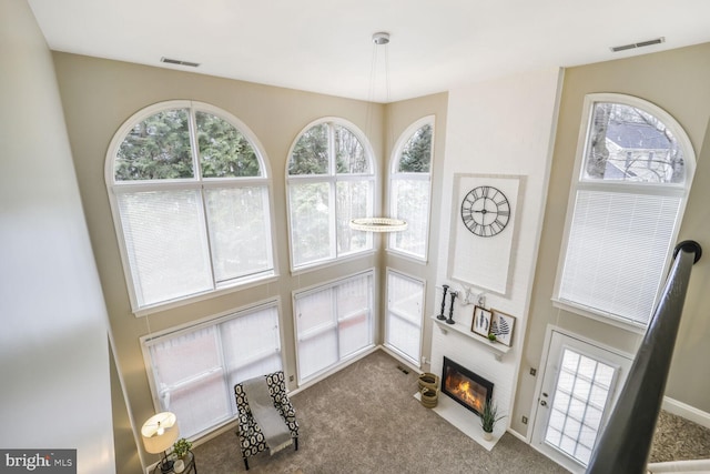 carpeted living area featuring visible vents, plenty of natural light, and a fireplace