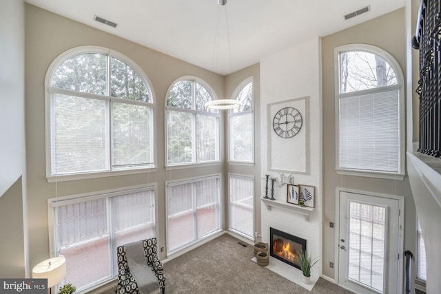 living area featuring a fireplace, visible vents, and carpet flooring