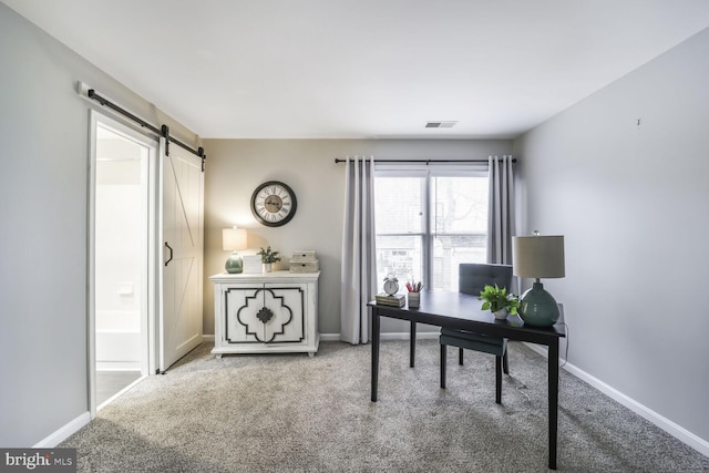 carpeted home office featuring a barn door, visible vents, and baseboards