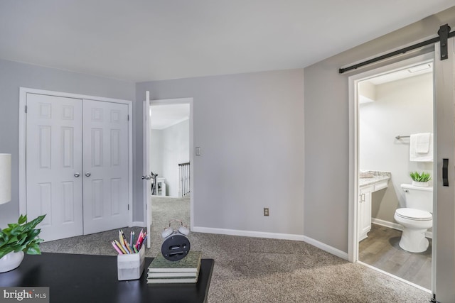 interior space featuring carpet, a barn door, and baseboards