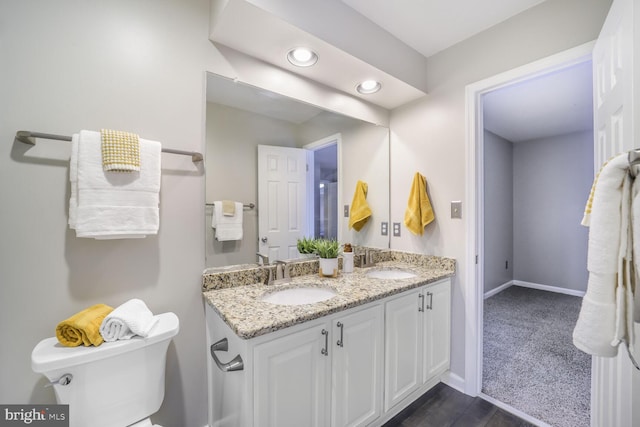 bathroom with baseboards, a sink, toilet, and double vanity