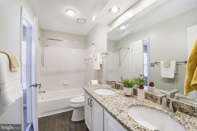 bathroom featuring toilet, double vanity, a sink, and wood finished floors