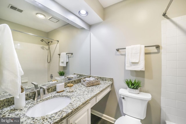 full bathroom with toilet, vanity, a tile shower, and visible vents