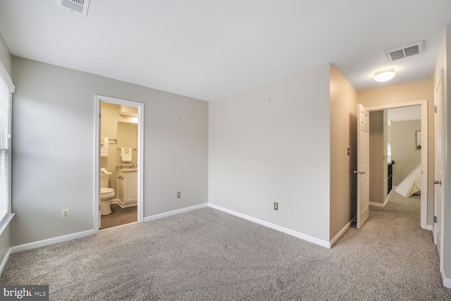 unfurnished bedroom with carpet floors, visible vents, connected bathroom, and baseboards