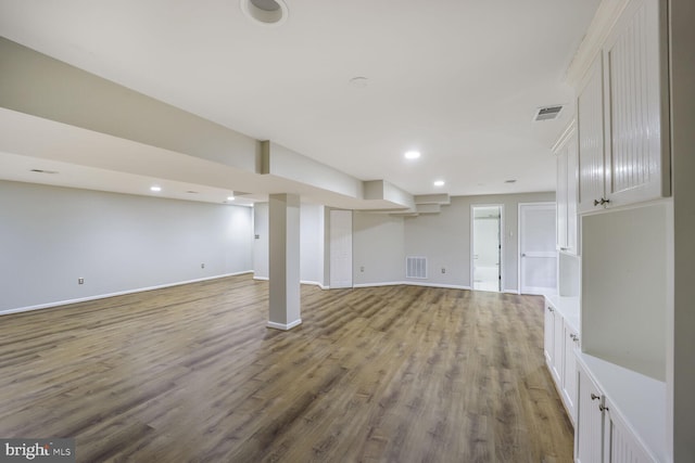 finished below grade area with baseboards, visible vents, and wood finished floors