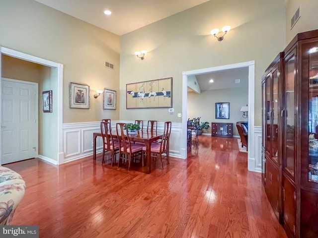 dining area featuring wood finished floors, visible vents, and a decorative wall