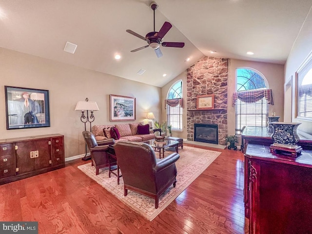 living area featuring baseboards, ceiling fan, wood finished floors, vaulted ceiling, and a fireplace