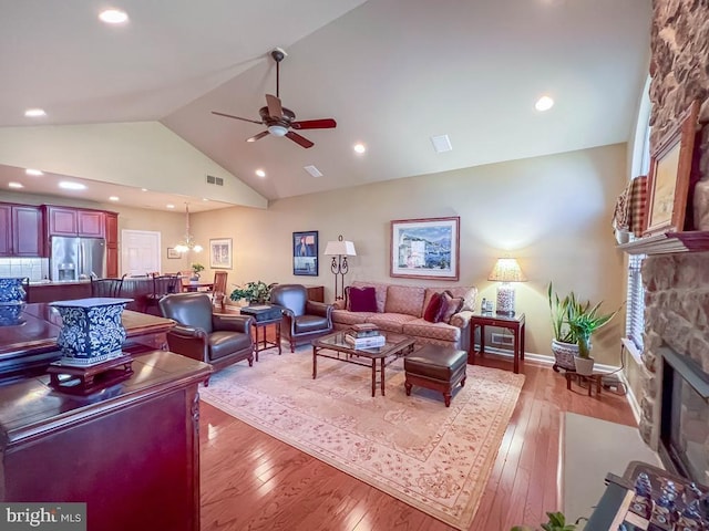 living area with high vaulted ceiling, light wood finished floors, a fireplace, and visible vents