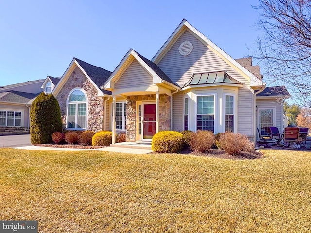 view of front of house featuring metal roof, stone siding, a standing seam roof, and a front yard