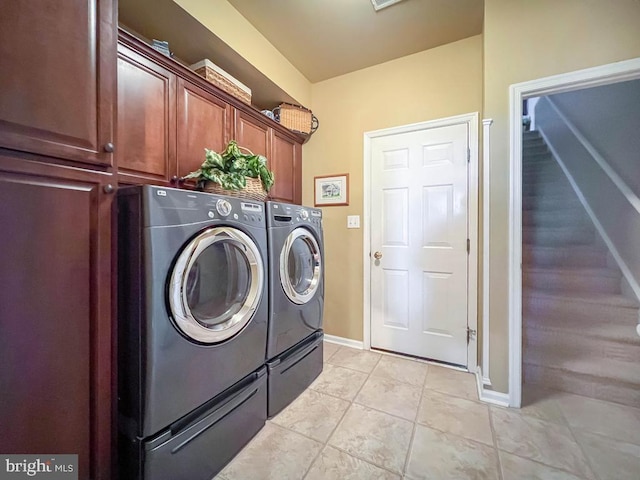 laundry area featuring cabinet space, light tile patterned floors, baseboards, and washer and dryer