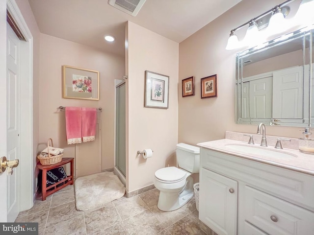 bathroom featuring toilet, vanity, a shower stall, and visible vents