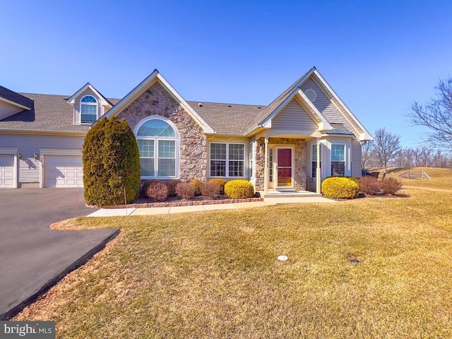 view of front of property with a garage, stone siding, driveway, and a front lawn