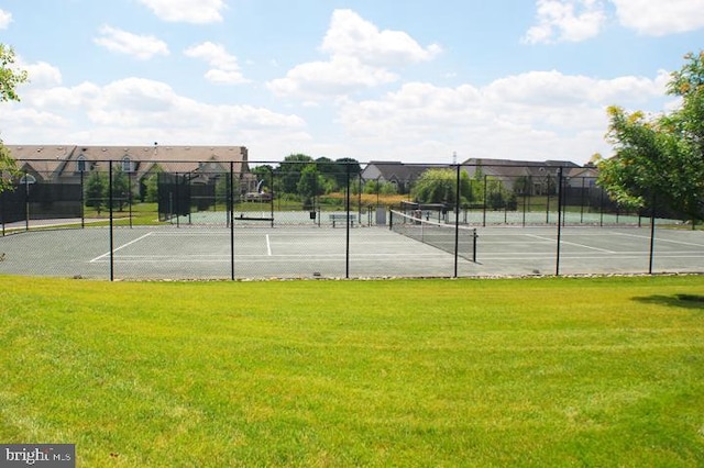 view of tennis court with fence and a lawn