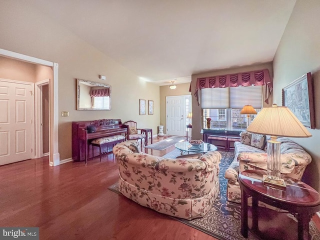 living area with vaulted ceiling, baseboards, and wood finished floors