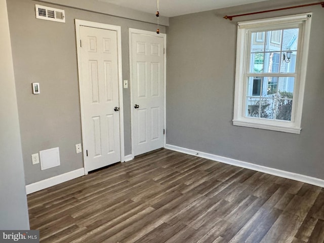 unfurnished bedroom with baseboards, visible vents, and dark wood-type flooring