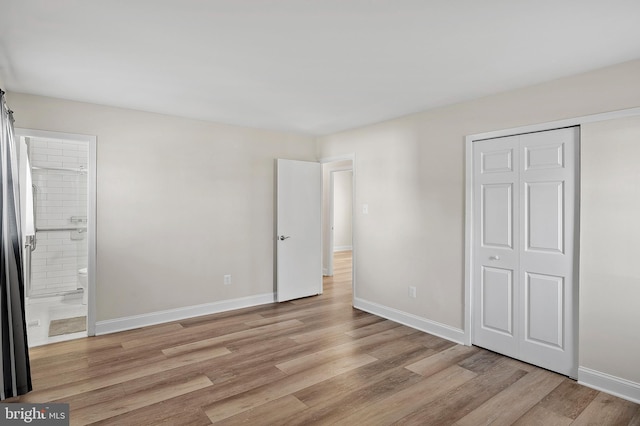 unfurnished bedroom featuring light wood-type flooring, baseboards, a closet, and ensuite bathroom