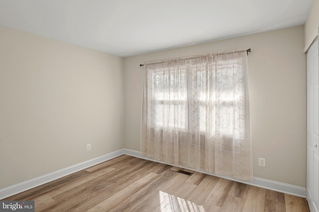 spare room with visible vents, baseboards, and wood finished floors