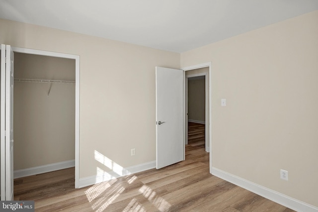 unfurnished bedroom with a closet, baseboards, and wood finished floors