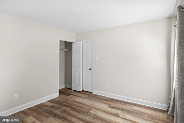 unfurnished bedroom featuring a closet, baseboards, and wood finished floors