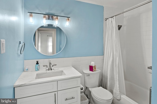 bathroom with a wainscoted wall, shower / tub combo with curtain, tile walls, toilet, and vanity