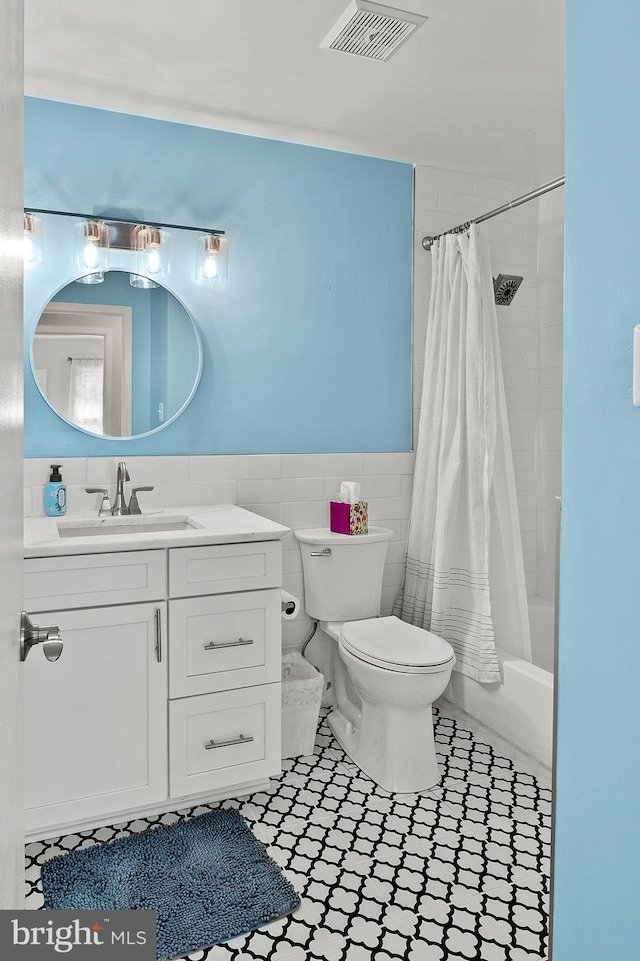 bathroom with visible vents, toilet, a wainscoted wall, vanity, and tile walls