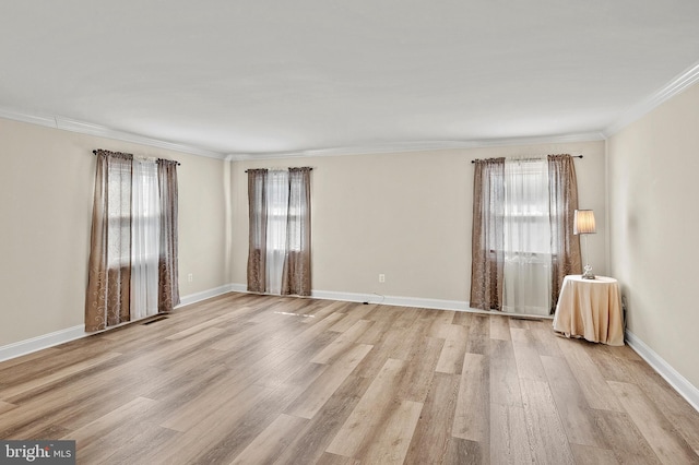 empty room with ornamental molding, light wood finished floors, a wealth of natural light, and baseboards