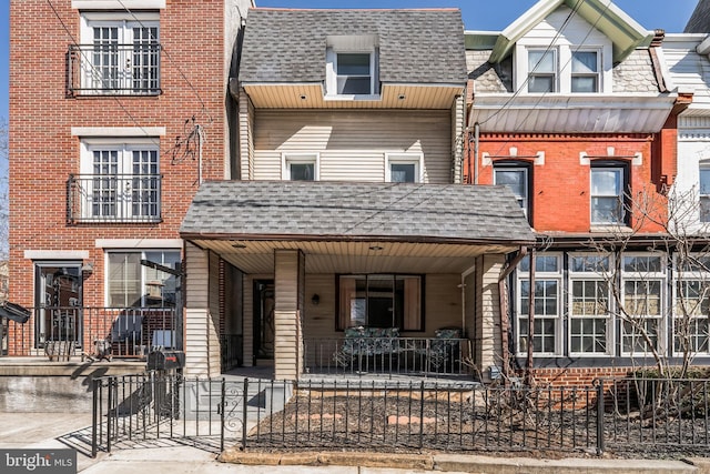 townhome / multi-family property with a shingled roof and a porch