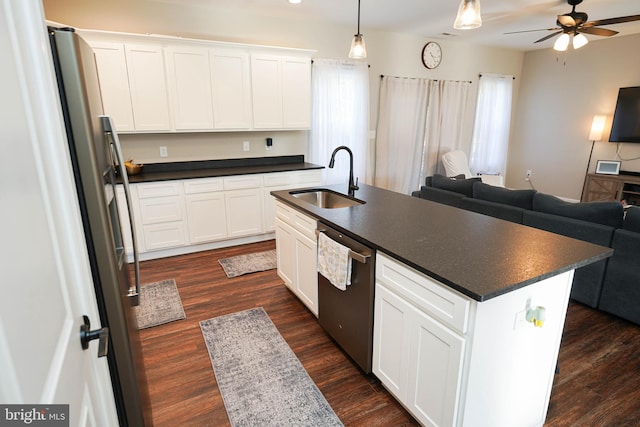 kitchen featuring stainless steel appliances, a sink, white cabinets, an island with sink, and dark countertops