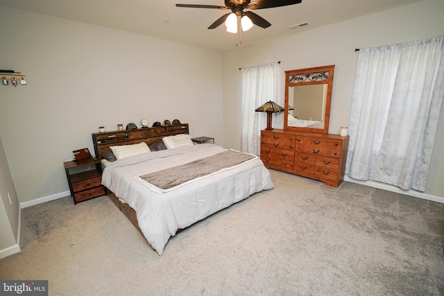 bedroom with a ceiling fan, visible vents, light carpet, and baseboards