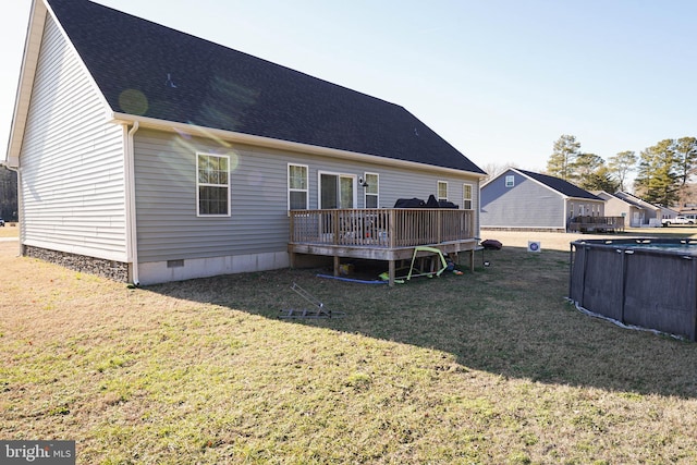 rear view of house with a shingled roof, an outdoor pool, crawl space, a deck, and a yard