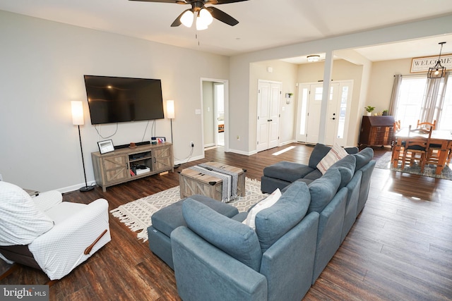 living room featuring ceiling fan, baseboards, and dark wood-type flooring