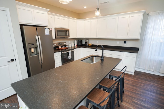 kitchen featuring white cabinets, a center island with sink, stainless steel appliances, and a sink