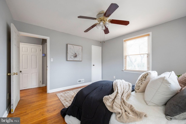 bedroom with a ceiling fan, light wood-type flooring, visible vents, and baseboards