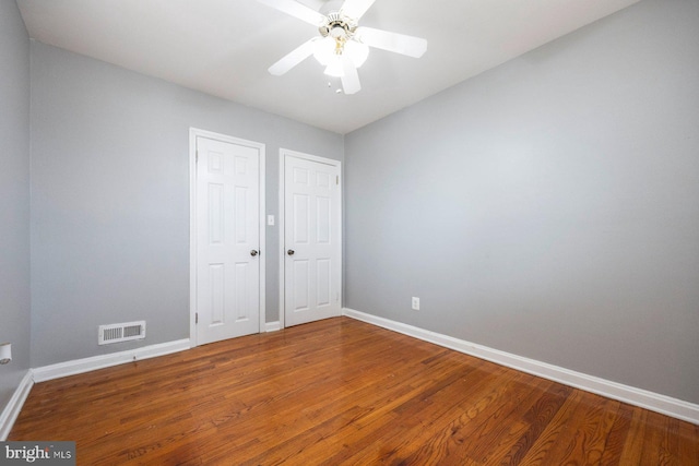 unfurnished bedroom with a ceiling fan, visible vents, baseboards, and wood finished floors