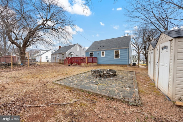 back of property featuring a fire pit, a chimney, a residential view, a deck, and an outdoor structure