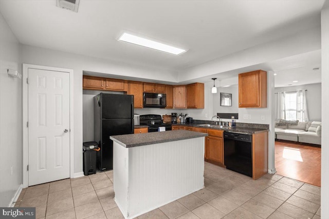 kitchen featuring black appliances, dark countertops, a sink, and brown cabinets