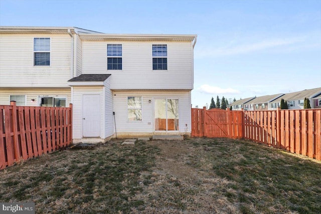 rear view of house featuring a fenced backyard and a lawn