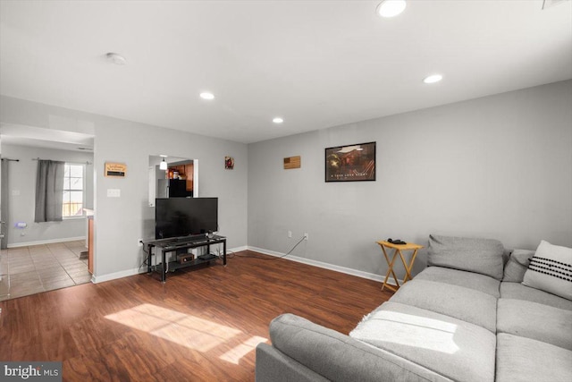 living area with baseboards, wood finished floors, and recessed lighting