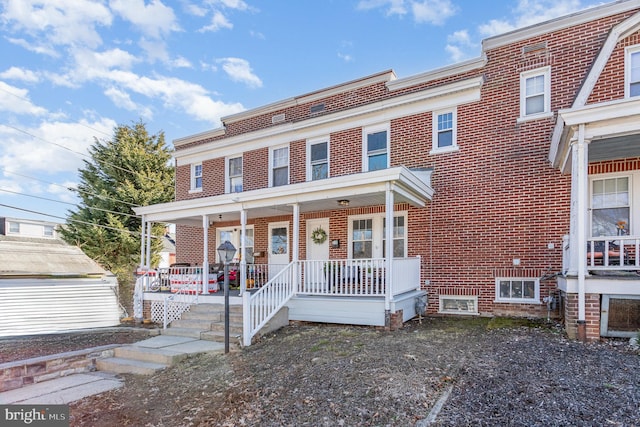 multi unit property featuring covered porch and brick siding