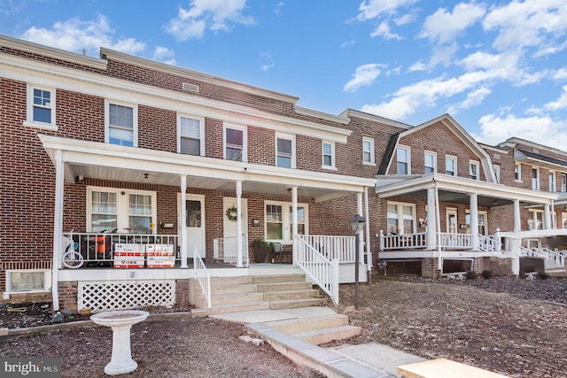 view of property with covered porch and brick siding