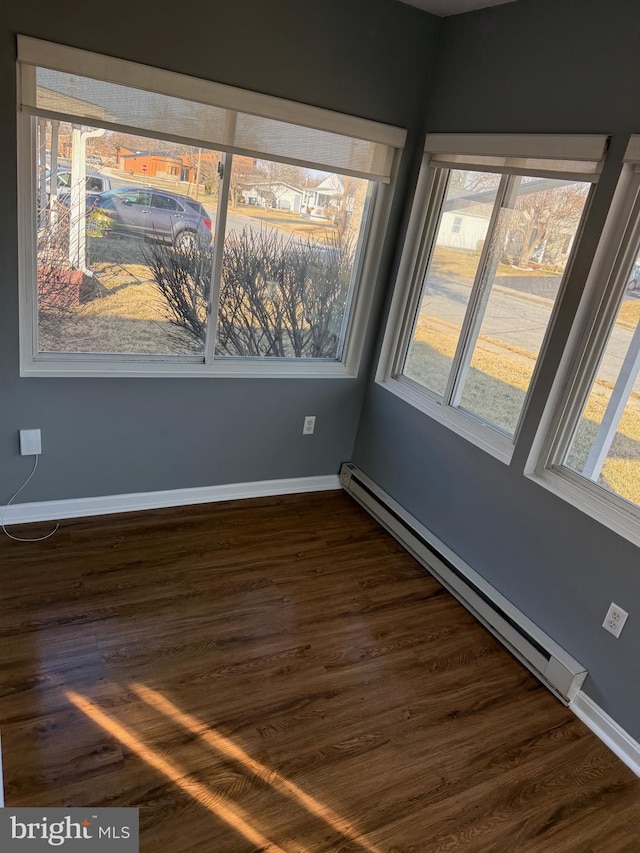 unfurnished room with a baseboard radiator, baseboards, and dark wood finished floors