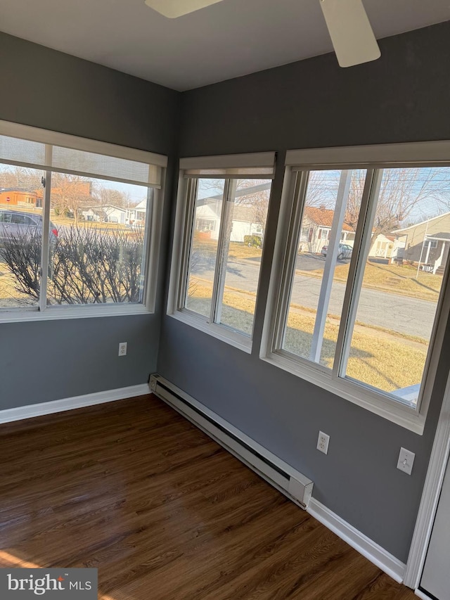 spare room with a baseboard radiator, dark wood finished floors, and baseboards