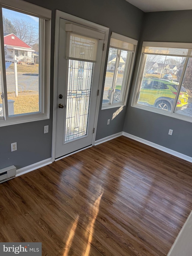 doorway to outside with a baseboard heating unit, dark wood-style flooring, and baseboards